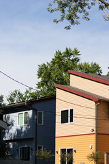 modern houses neighborhood, Blue and yellow slanted roof houses vertical modern trees in the background powerlines