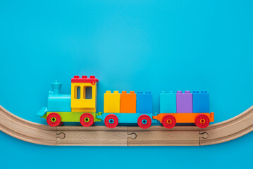 Toys background with copy space. Kids toy train with two carriages on wooden railway  on blue...