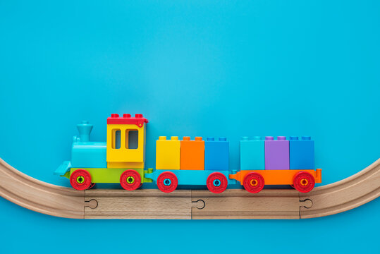 Toys background with copy space. Kids toy train with two carriages on wooden railway  on blue background with copy space for text