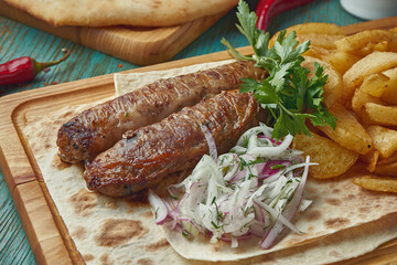 Grilled Turkish lamb lula kebab with potato, onion and rice on a wooden board. Wooden background.