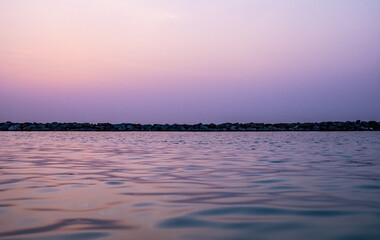 Calm water of the sea merging with the color of the sky with rocks in the background