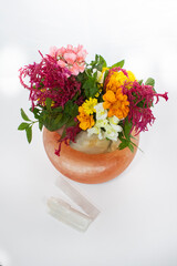 foraged colorful flower arrangement. Foraged flowers arranged on a Himalayan salt rock on a white backdrop