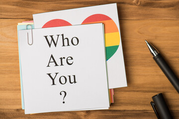 Who are you concept. Photo above of notes with paperclips and pen isolated on the wooden background