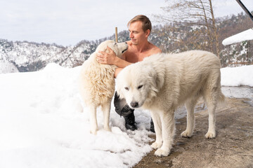 Man with a naked torso, two white dogs, snow