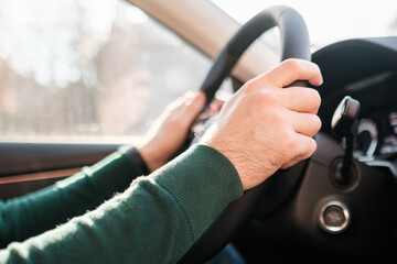 Close up mans hands on the wheel, driving a car. 