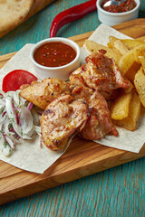 An appetizing oriental dish - grilled chicken or beef kebab with a side dish of potatoes and onions with red onions on a green background. Georgian cuisine. Shish kebab