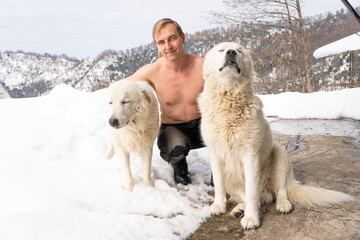 Man with a naked torso, two white dogs, snow
