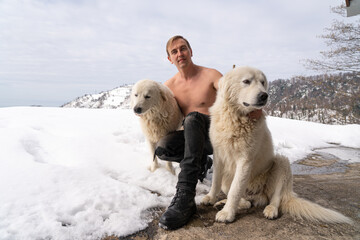 Man with a naked torso, two white dogs, snow