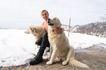Man with a naked torso, two white dogs, snow