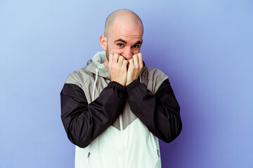 Young caucasian bald man isolated on purple background biting fingernails, nervous and very anxious.