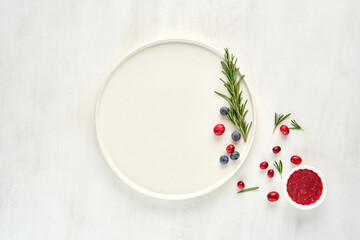 White plate decorated with berries top view, flat lay