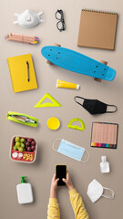 Flat lay top view of child with smartphone and school supplies, distance learning and coronavirus concept.