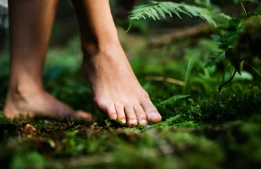 Foto op Aluminium Bare feet of woman standing barefoot outdoors in nature, grounding concept. © Halfpoint