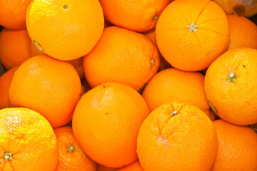 front view, close up of a pile of freshly picked, ripe, local oranges on display and for sale at a tropical fruit store