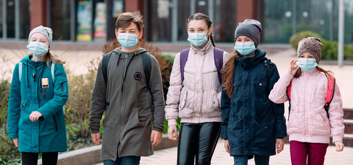 Children students in medical masks leave the school.
