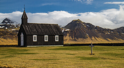 Budir church in Iceland with mountains covered with little bit of snow in april