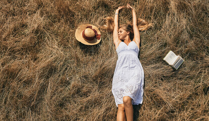 Young woman reading a book lying in grass