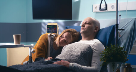 Wife hugging husband in cancer clinic
