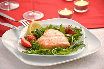 Roasted salmon with fresh rocket and strawberry on the table