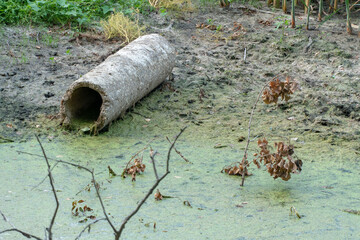 dirty water in the river. Environmental pollution. Construction waste. The asbestos pipe lies on...