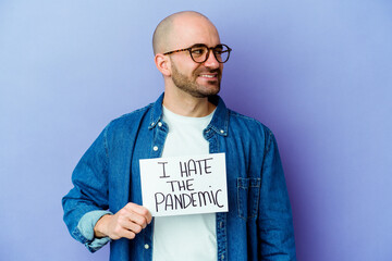 Young caucasian bald man holding a I hate the pandemic placard isolated on blue background looks...