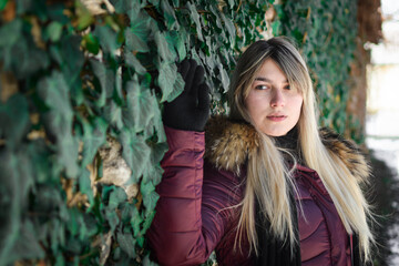 Portrait of a young girl from eastern Serbia. Posing by the wall covered with green leaves.