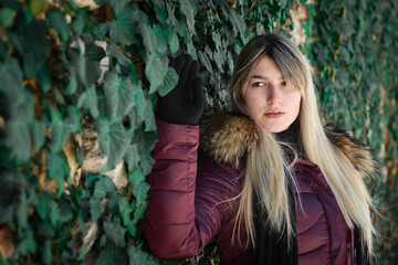 Portrait of a young girl from eastern Serbia. Posing by the wall covered with green leaves.