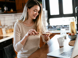 Beautiful woman eating breakfast in the kitchen. Happy woman making sandwich ..