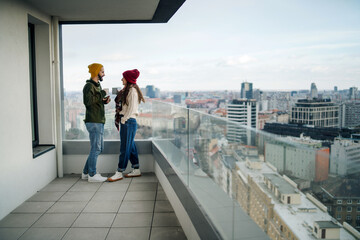Young couple owners with coffee on balcony in new flat, moving in, new home and relocation concept.