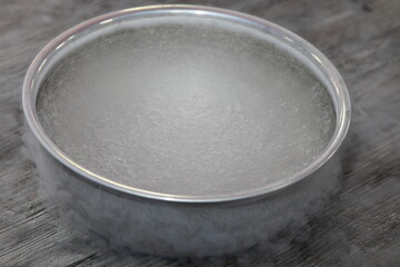 Stainless steel bowl with liquid nitrogen on table close up top side view