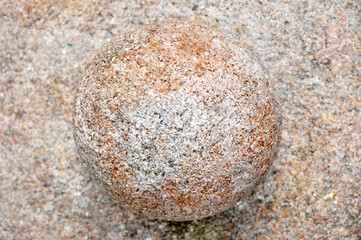 Round stone on a textured sandy surface