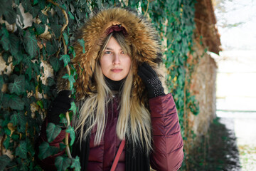 Portrait of a young girl from eastern Serbia. Posing by the wall covered with green leaves.