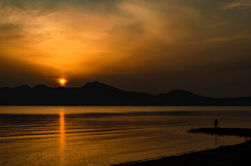 Obraz premium Sunrise yellow orange sky with man fishing 