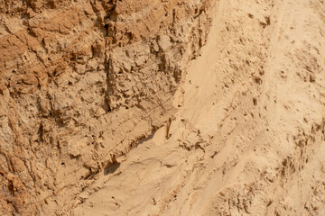 The steep slope of a sand mining quarry. Background and texture of sand. soil layers on a plot of the cut of the soil during a geological survey.