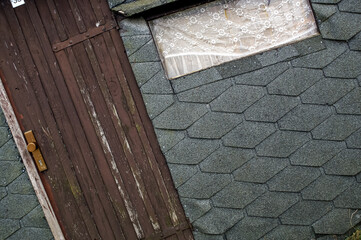 old wooden door and a window on a boathouse with tar paper