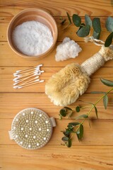 Body skin care. Natural bristle brushes, sea salt, body scrub, natural stone roller, brush on wooden background