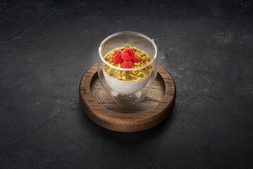 Healthy vegetarian dessert in glass with chia pudding and fresh raspberry on dark slate background