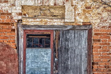 Gray wooden door on the brick wall of an abandoned house