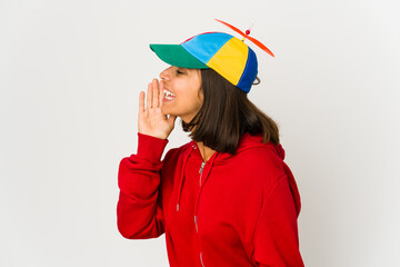 Young hispanic woman wearing a cap with propeller isolated shouting and holding palm near opened mouth. © Asier