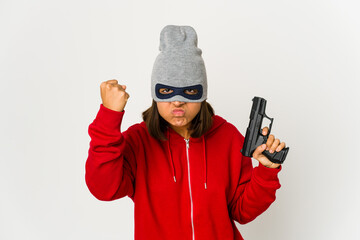 Young robber hispanic woman wearing a mask showing fist to camera, aggressive facial expression.