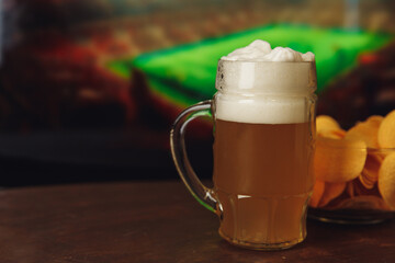 One glass of cold beer and chips, watching football at home.