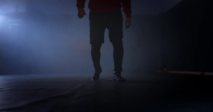 Close-up of an athlete's legs entering a dark gym with smoke. Athlete stands with his feet on the tatami. 4k, ProRes