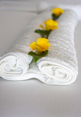 White towel with yellow flowers on clean bed. Oriental hotel household. Spa salon decoration. Resort room interior. Wellness and therapy service. Hotel decor with flower. Luxury travel concept. 
