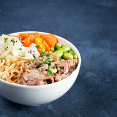Poke bowl, pulled pork, vegetables, pumkin, soy beans edamame, noodles, on bowl, chopsticks. Copy...