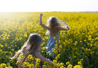 Children run across the yellow rapeseed field. Children in the spring.