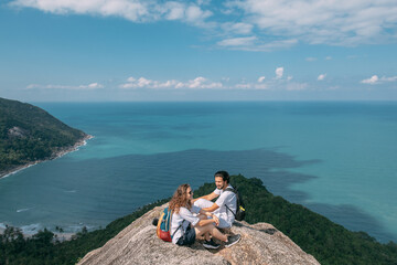 A couple stand on a rock at a viewpoint with an epic view of the ocean