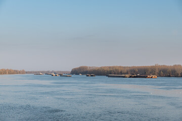 Oil and cargo barges anchored on the river with the anchor lowered into the water waiting for the...