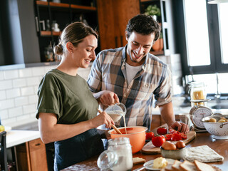Husband and wife in kitchen. Young couple preparing delicious food at home.