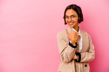 Young business mixed race woman isolated on pink background points with thumb finger away, laughing and carefree.