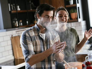 Husband and wife in kitchen. Young couple playing with flour while baking.